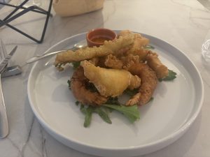 Plate of assorted tempura including shrimp and vegetables on a bed of greens