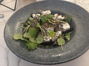 Plated dish with seared tuna slices topped with cream, microgreens, and shaved truffle